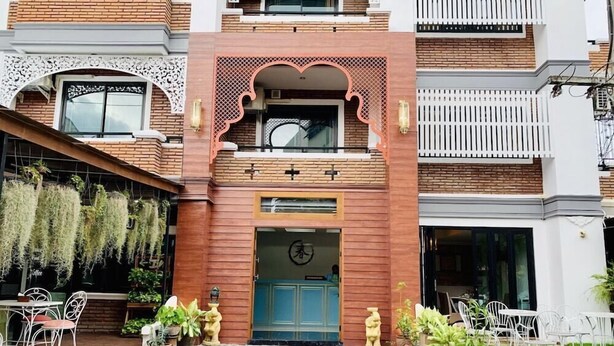 A building with a central entrance, a balcony, and a small outdoor seating area with tables and chairs. - TJR Boutique House (Chiang Mai)