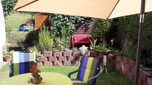 An outdoor patio with a round table, two striped chairs, and a red chair.