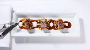 Une assiette rectangulaire blanche contenant un plat composé de viande, de légumes et de sauce.