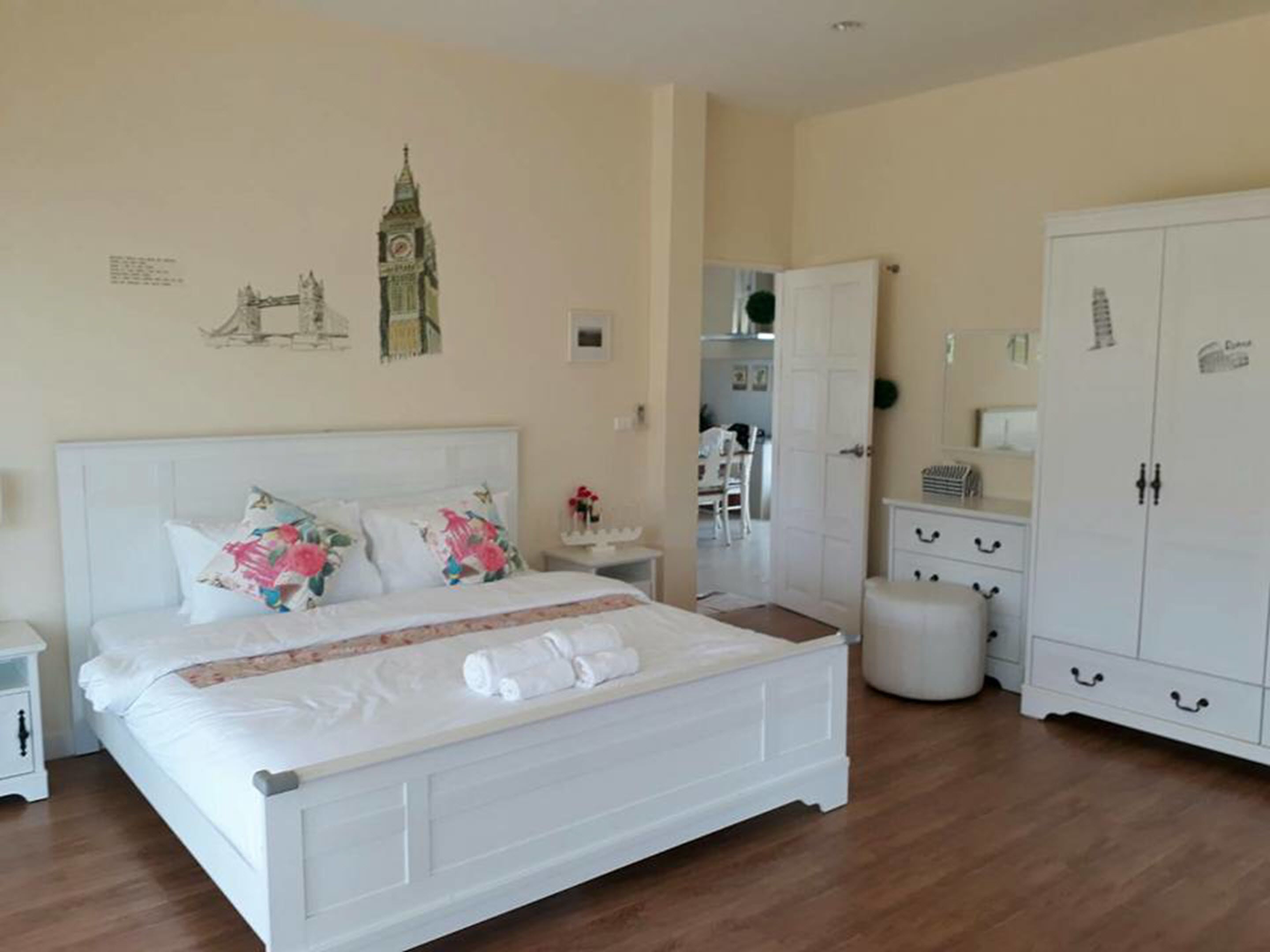 A bedroom with a white bed, a wardrobe, and a mirror.