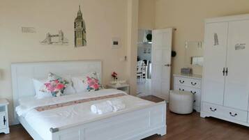 A bedroom with a white bed, a wardrobe, and a mirror.