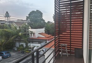 A balcony with a view of a residential area, including a white building with a red roof and a water tower in the background. - You and Me Hostel (Chiang Mai)
