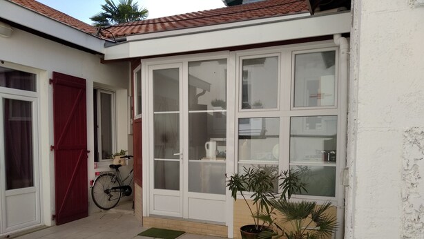 A small house with a tiled patio, a red door, a bicycle, and potted plants. - Cozy 2-Bedroom House near Arcachon Center & Beach (Arcachon)