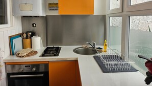 A kitchen with a stove, sink, and window. - Cozy 2-Bedroom House near Arcachon Center & Beach (Arcachon)