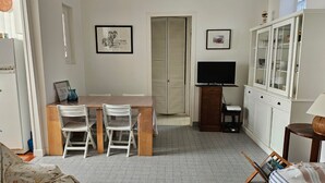A compact living space with a dining area, a television, and a cabinet. - Cozy 2-Bedroom House near Arcachon Center & Beach (Arcachon)