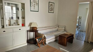 A cozy living room with a sofa, a dining table, a cabinet, and two framed pictures on the wall. - Cozy 2-Bedroom House near Arcachon Center & Beach (Arcachon)