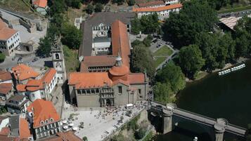An aerial view of a historic building with a prominent tower, a large courtyard, and a bridge over a river.