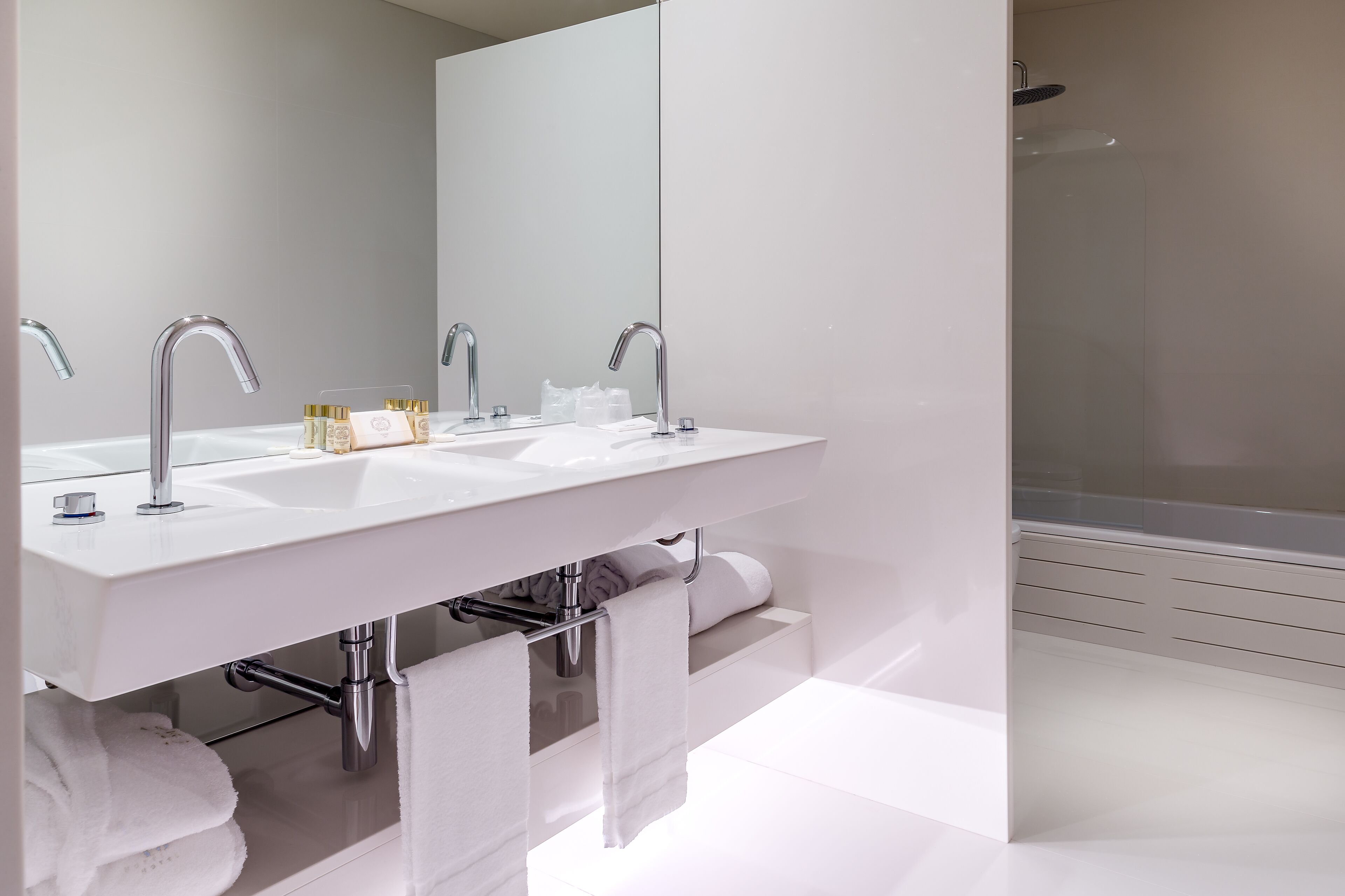 A modern bathroom with two sinks, a large mirror, and a shower.