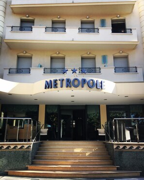 A hotel entrance with a double staircase leading up to a balcony with railings. - Hotel Metropole (Rimini)