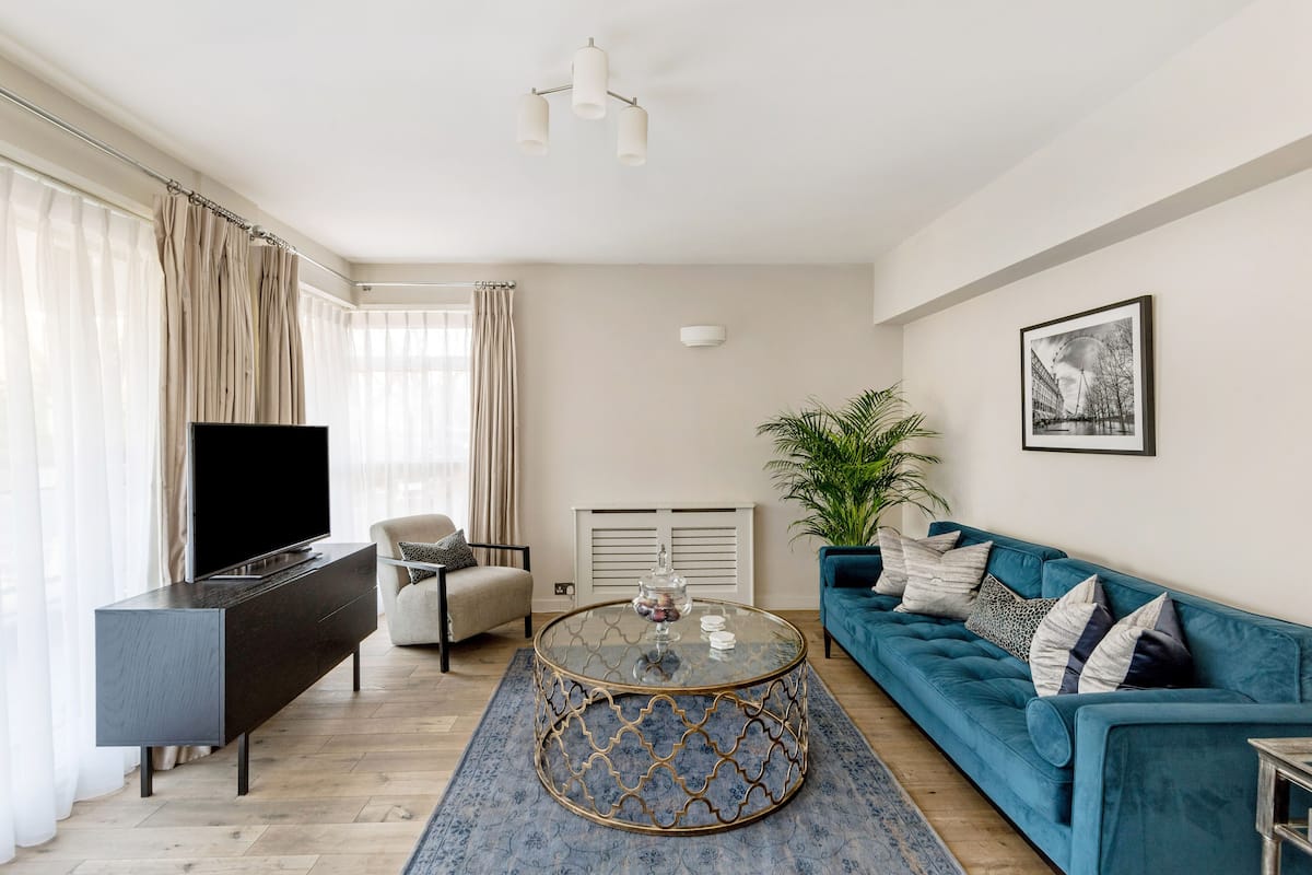 A modern living room with a sofa, a coffee table, a TV, and a plant.