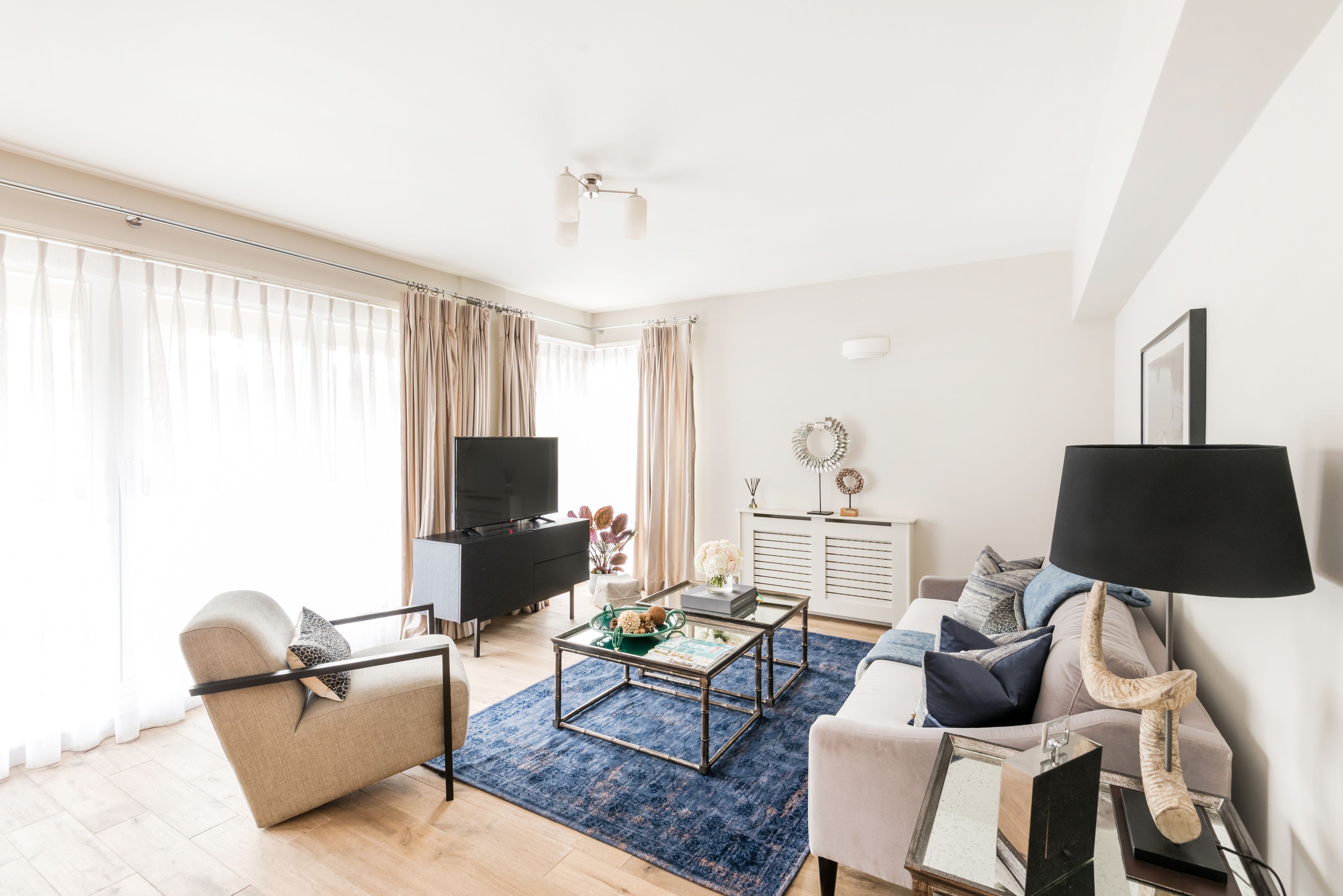 Una sala moderna con sofá, sillón, mesa de centro, televisor y lámpara.