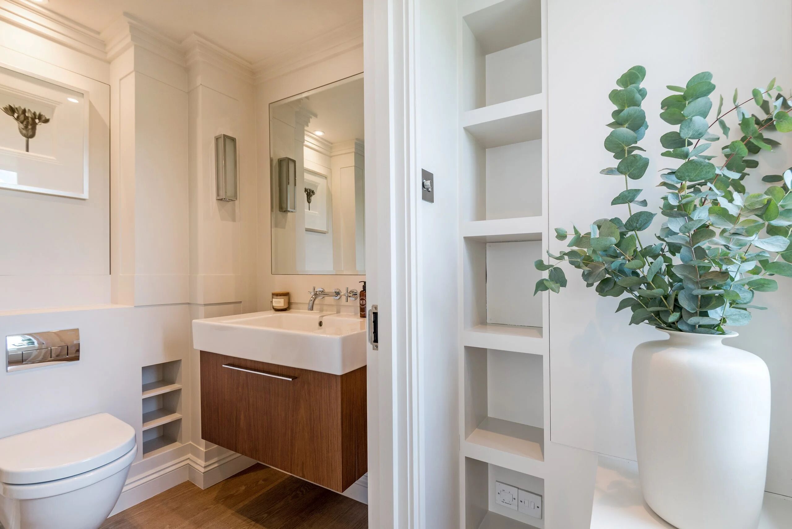 Un bagno moderno con lavandino bianco, mobiletto in legno e uno specchio grande.