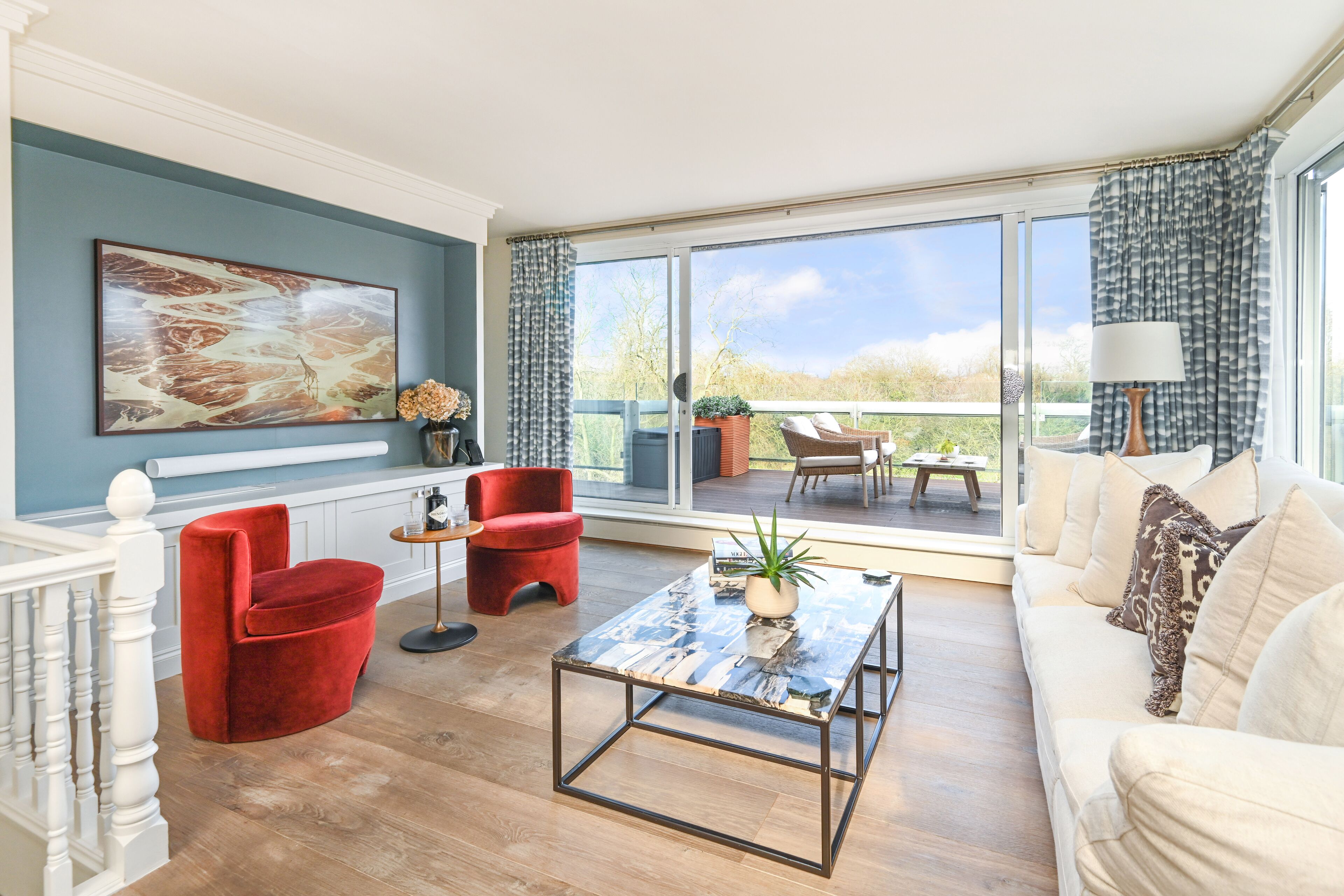 A spacious living room with a large window, a red chair, a white sofa, and a coffee table.