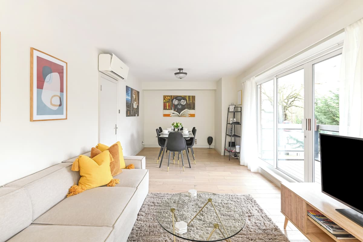A modern living room with a sofa, TV, and dining area.