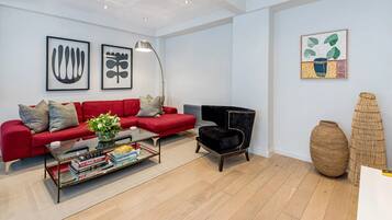 A modern living room with a red sofa, black armchair, and a glass coffee table with books.
