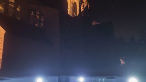 Vista nocturna de un edificio con una torre destacada y un área de piscina iluminada.