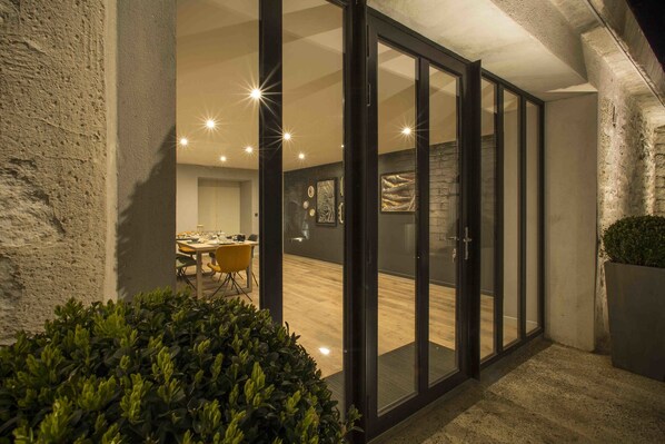 Un interior moderno con una zona de comedor, una escalera y un amplio ventanal que da a una habitación.