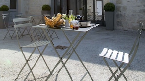 Un patio con una mesa y sillas, un ventanal grande y un edificio con una torre.