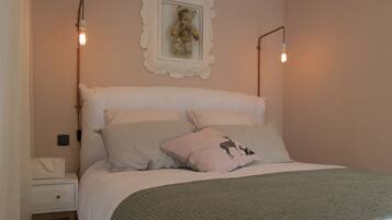 Une chambre à coucher bien rangée, avec un lit, des oreillers, une table de chevet et un luminaire fixé au mur.
