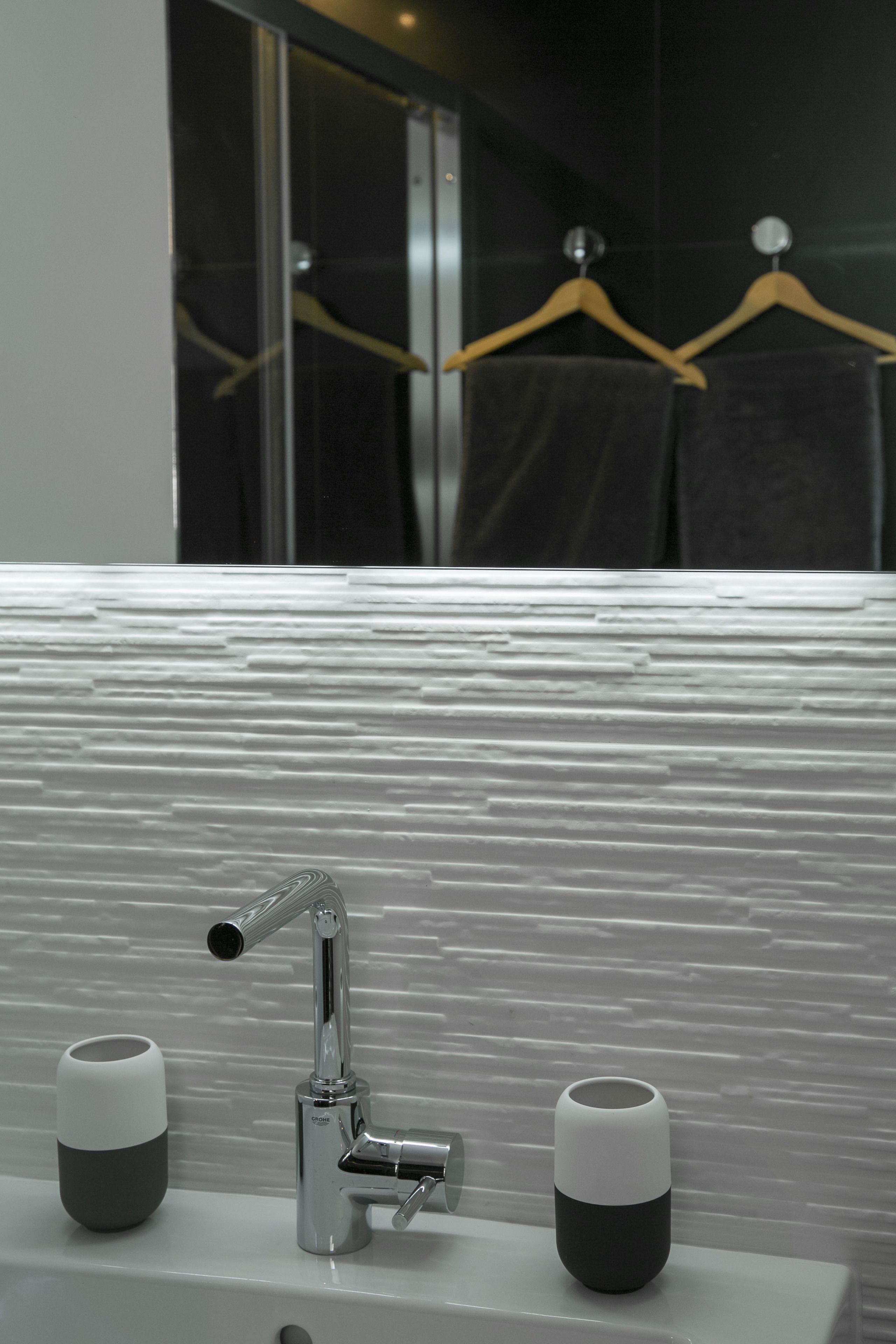 Un baño con un lavabo moderno, dos tazas y un perchero para toallas.