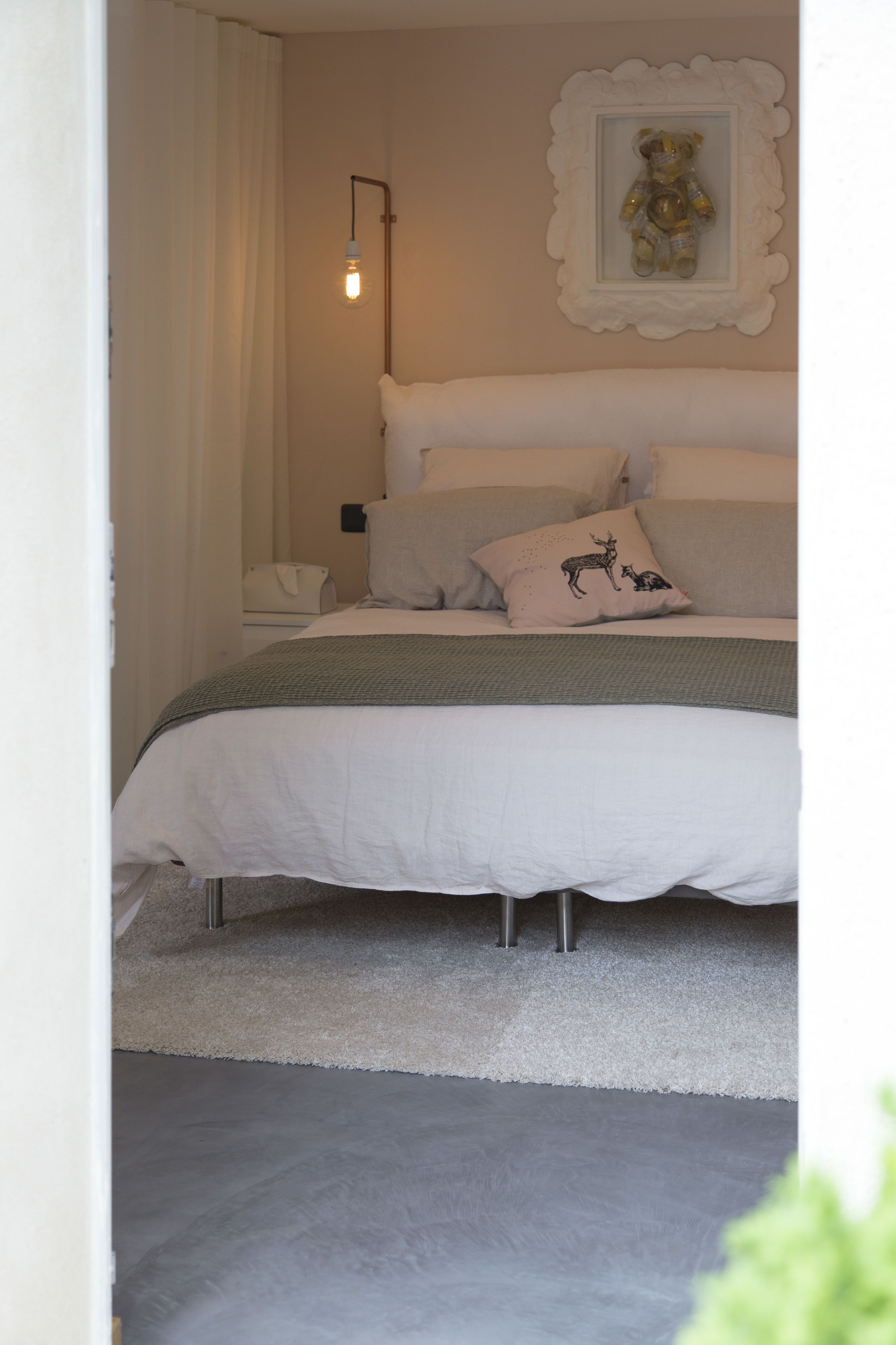 A bedroom with a bed, pillows, a bedside table, and a wall-mounted light.