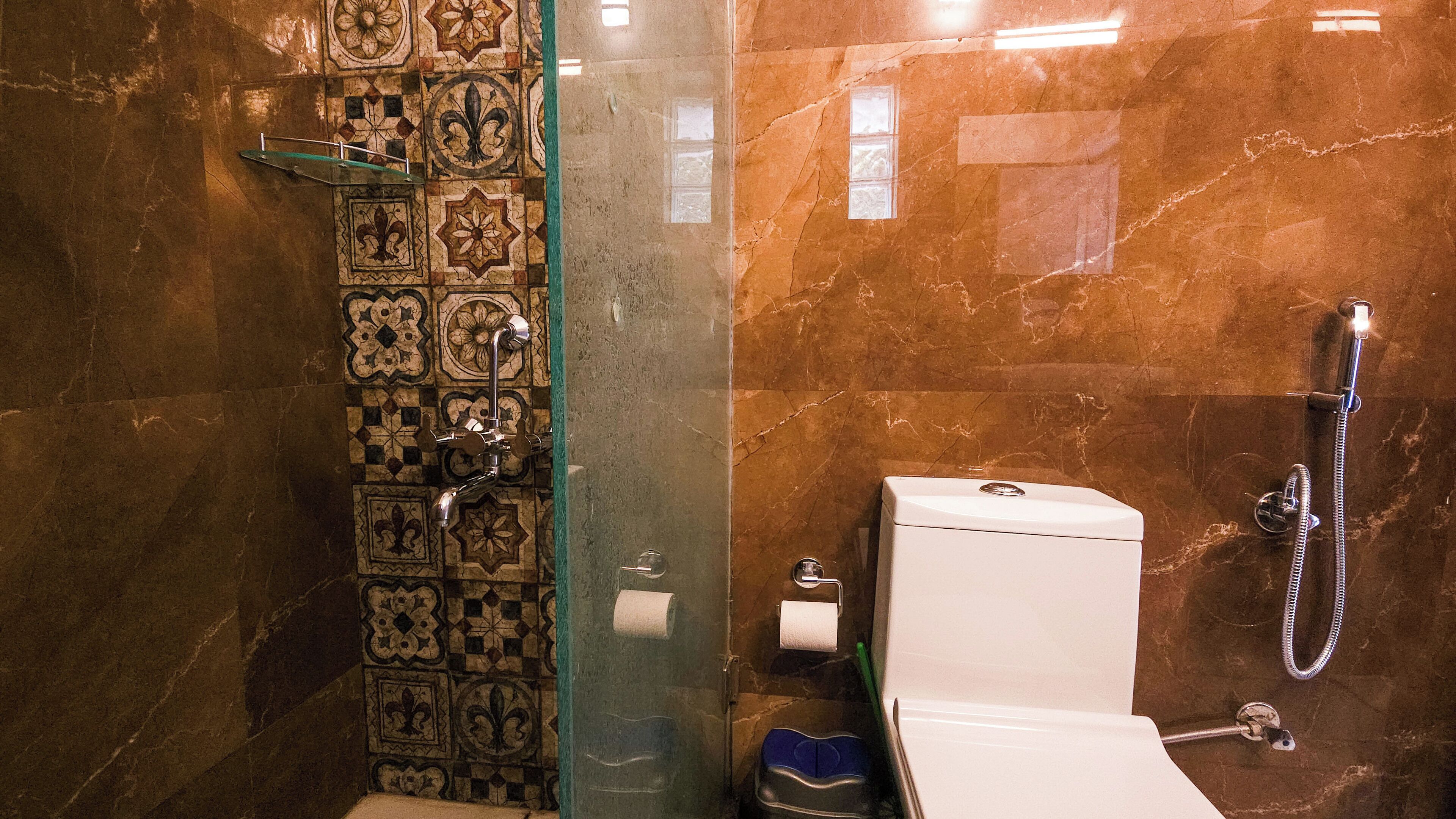 Een badkamer met douche, toilet en betegelde vloer.