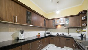 A modern kitchen with wooden cabinets, a black countertop, and stainless steel appliances. - Prakash Kutir B&B (New Delhi)