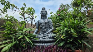 A seated Buddha statue surrounded by lush greenery. - Prakash Kutir B&B (New Delhi)