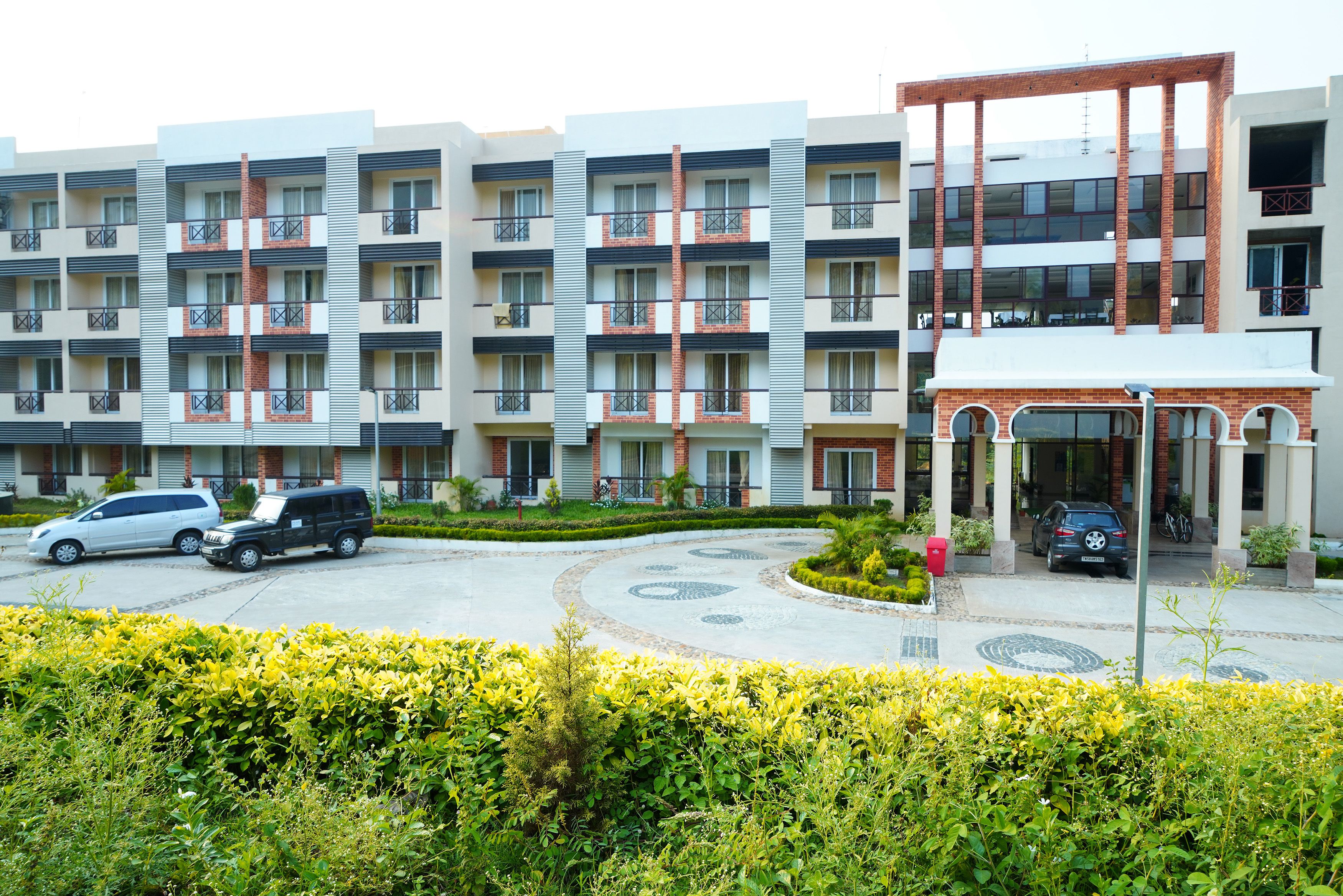 A multi-story hotel with a central courtyard, balconies, and a covered entrance.