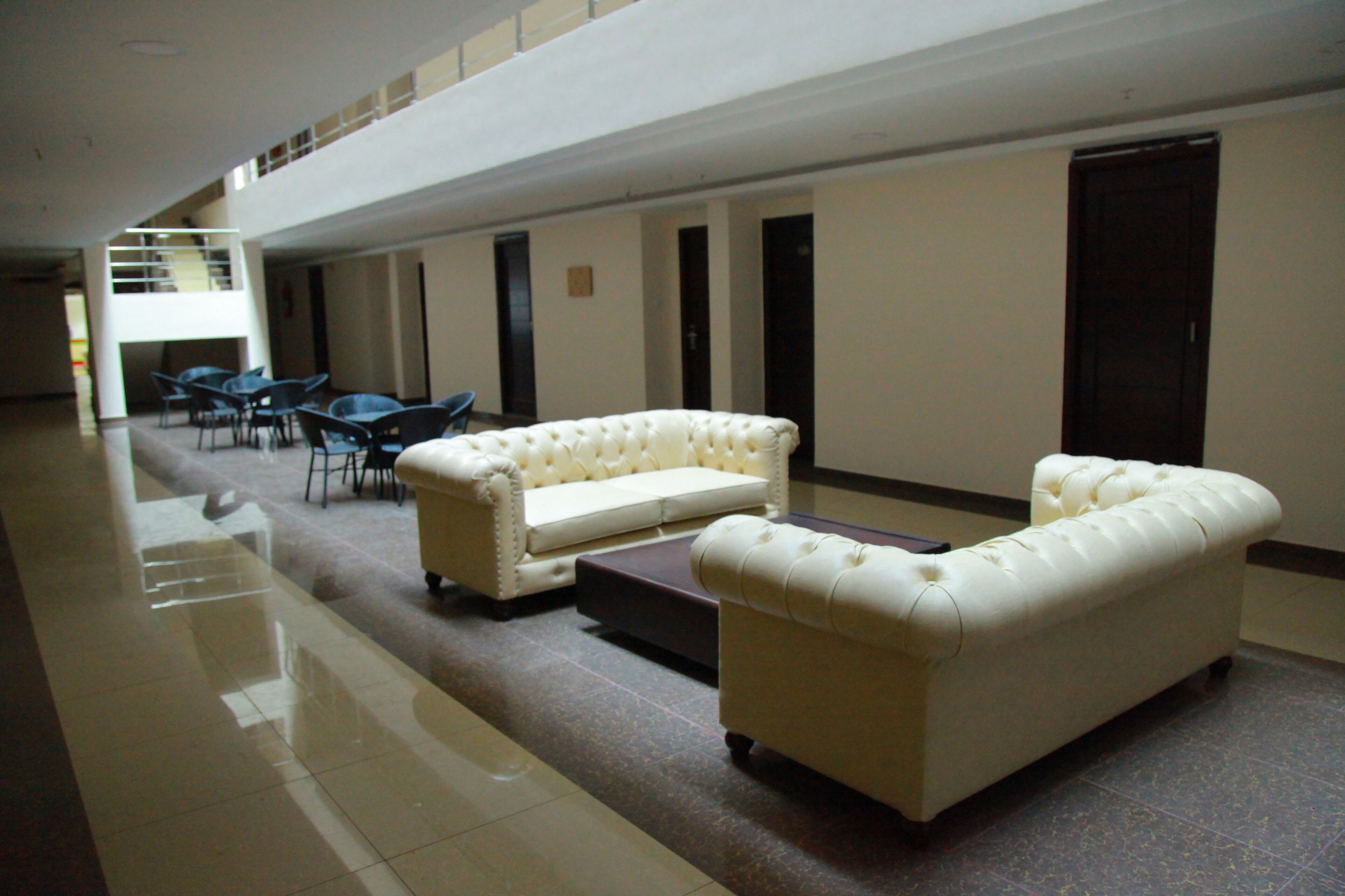 A spacious lobby with a white sofa, a matching armchair, and a dining table with chairs.
