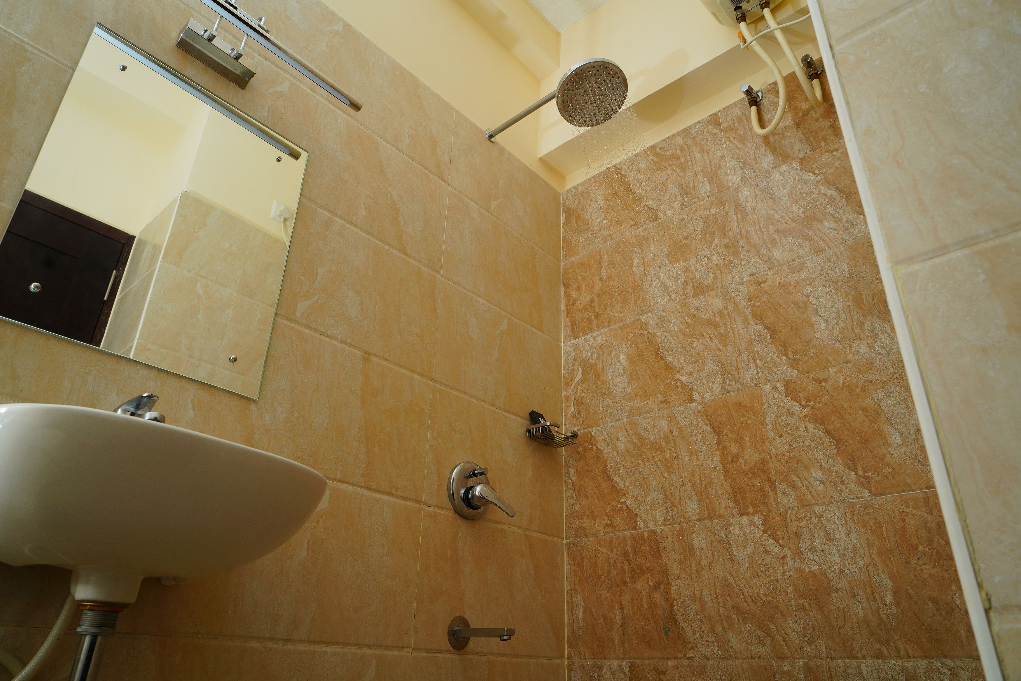 A bathroom with a sink, mirror, shower, and tiled walls.