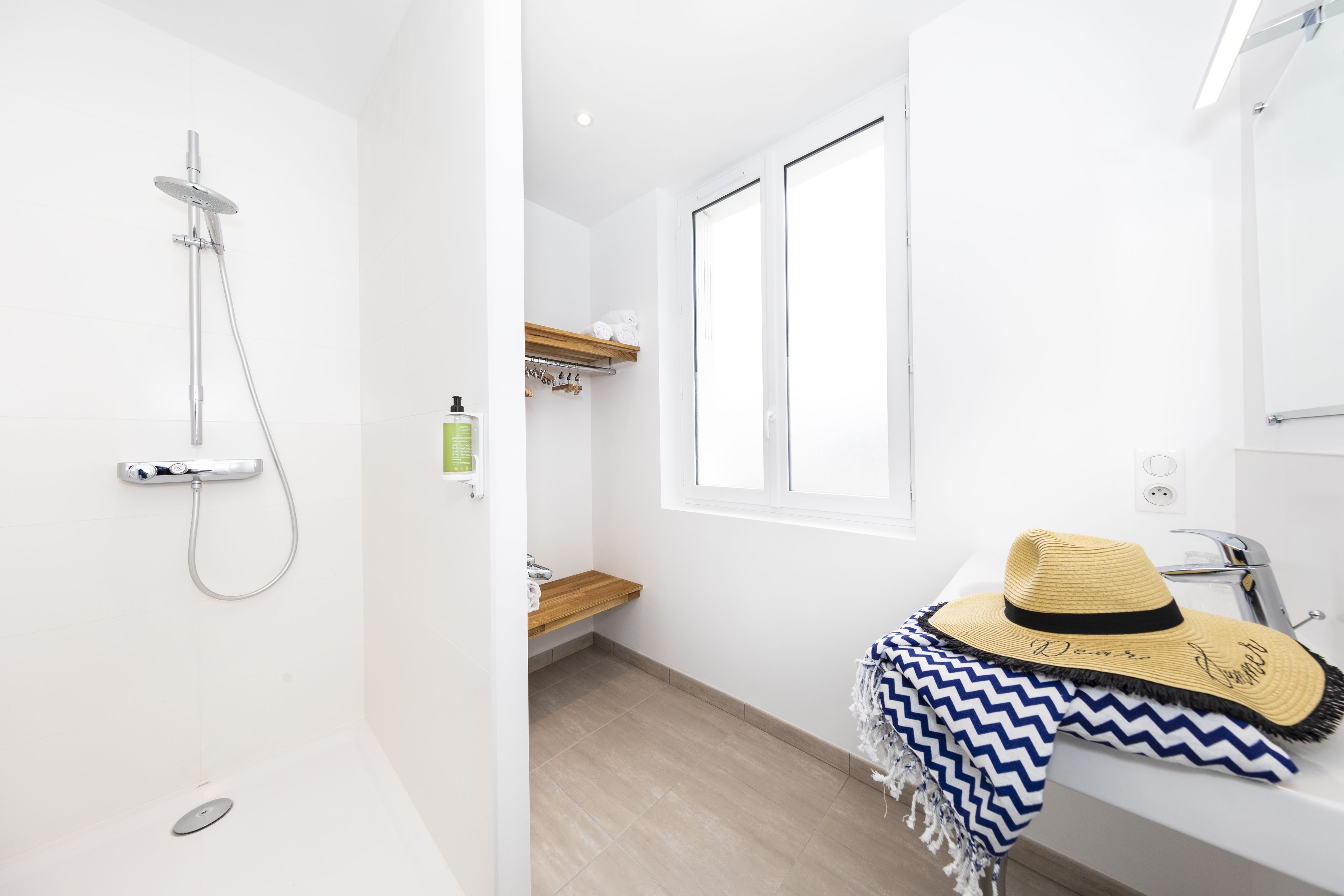 A modern bathroom with a shower, a sink, and a window.