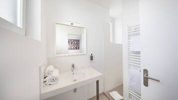 A modern bathroom with a white sink, mirror, and towel rack.