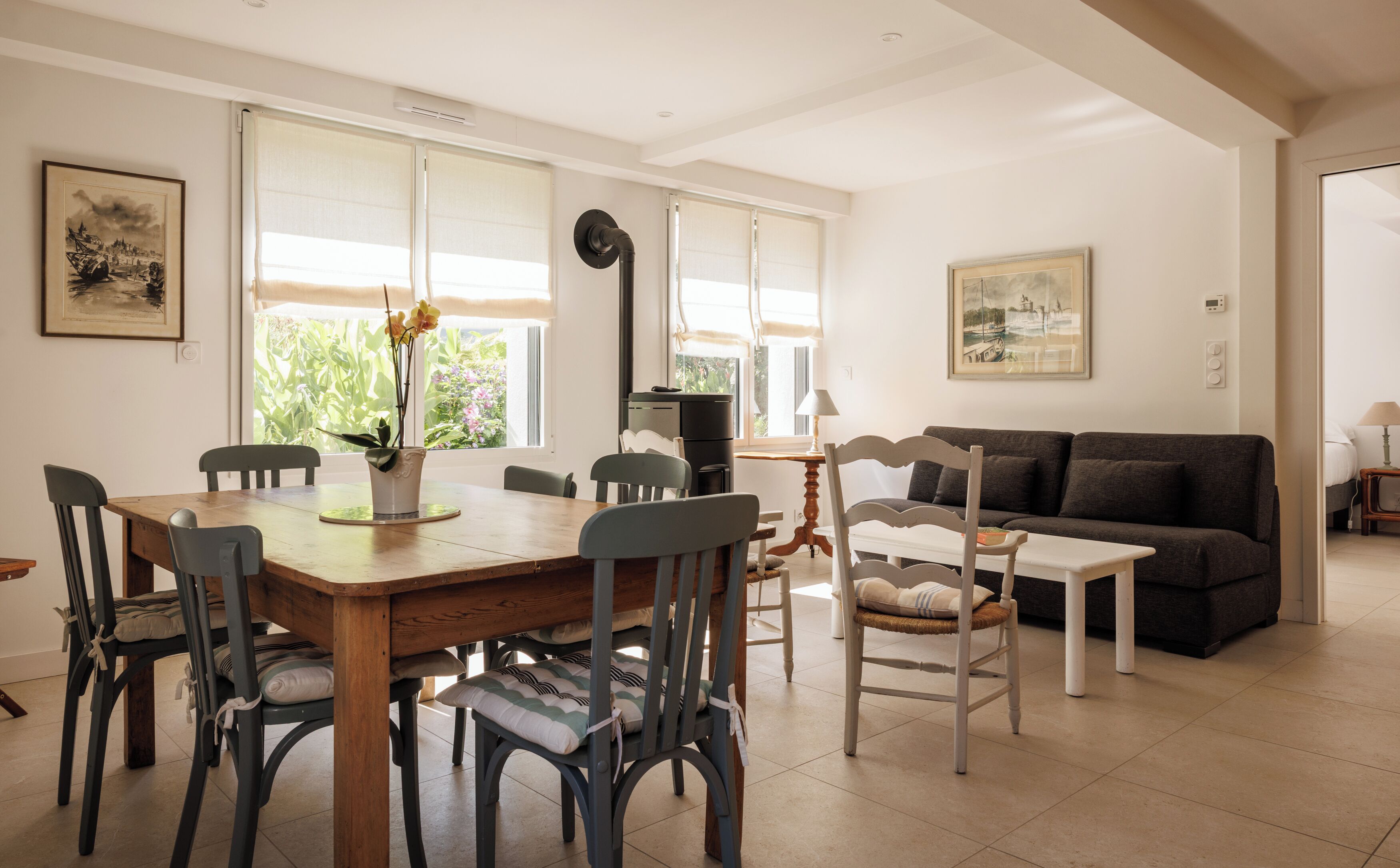 A dining area with a wooden table and chairs, a sofa, and a window with blinds.