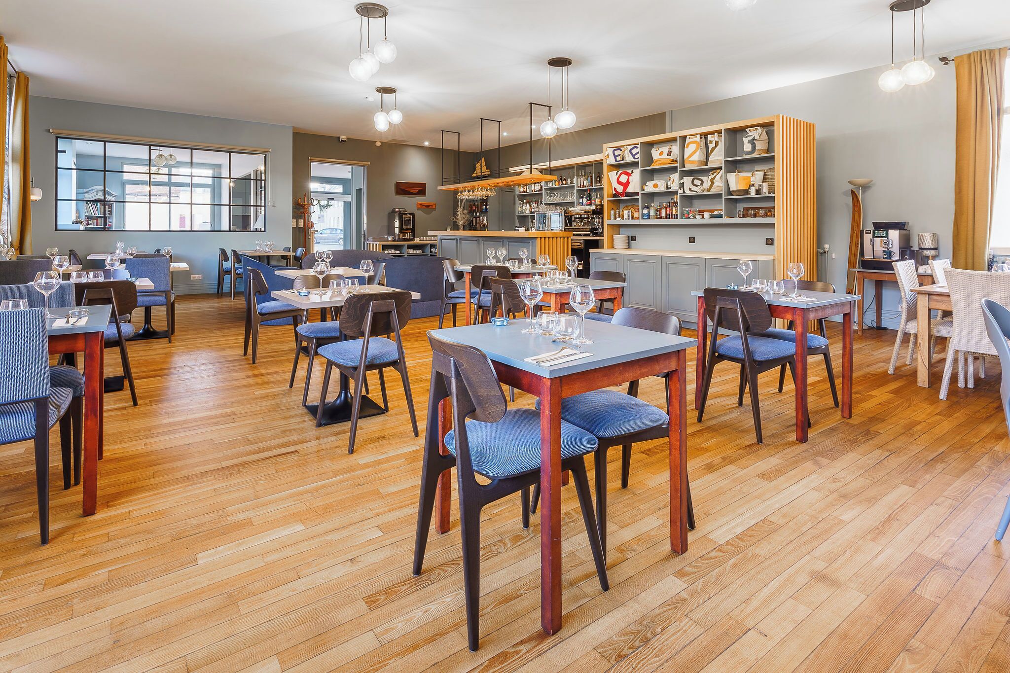 A restaurant with wooden floors, blue chairs, and tables set for dining.