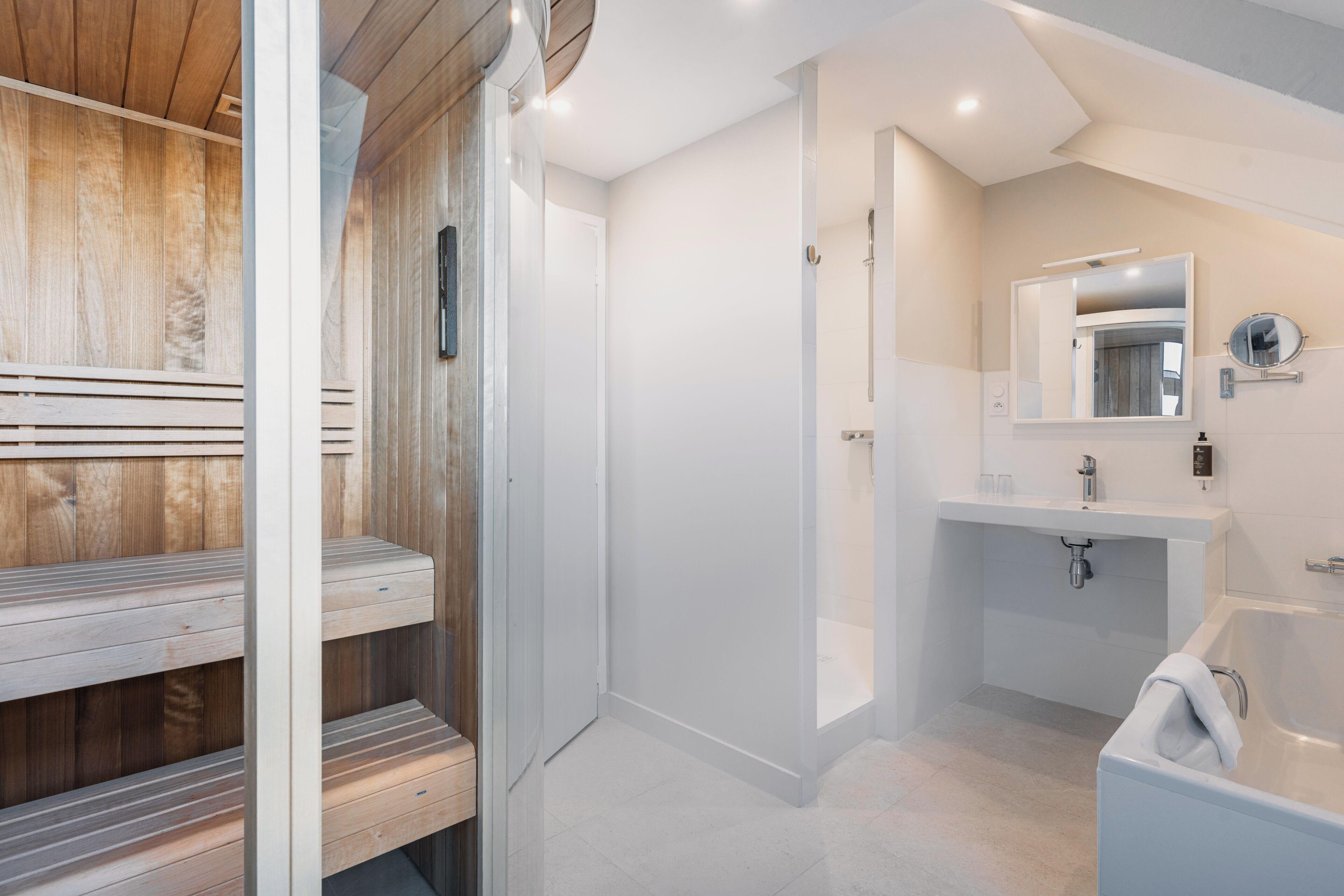Een moderne badkamer met een houten sauna, een witte wastafel en een grote spiegel.
