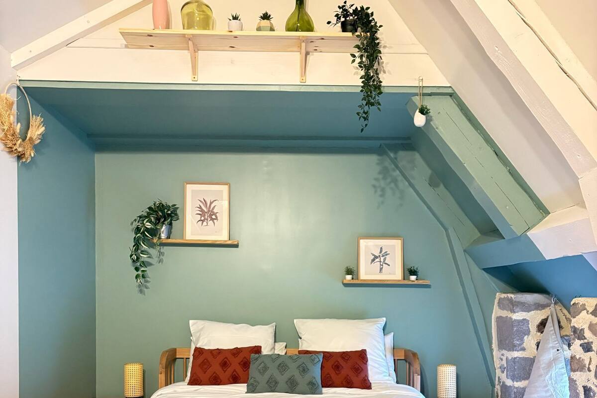 Een slaapkamer met een houten bed, nachtkastje, dressoir en een stenen muur.