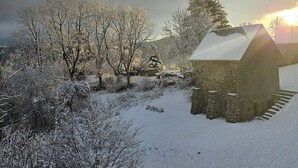 A snow-covered landscape with a stone building and trees. - Datcha Anastasia (Besse-et-Saint-Anastaise)