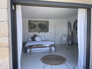 Une chambre à coucher avec un lit, une chaise, un tableau et une porte.