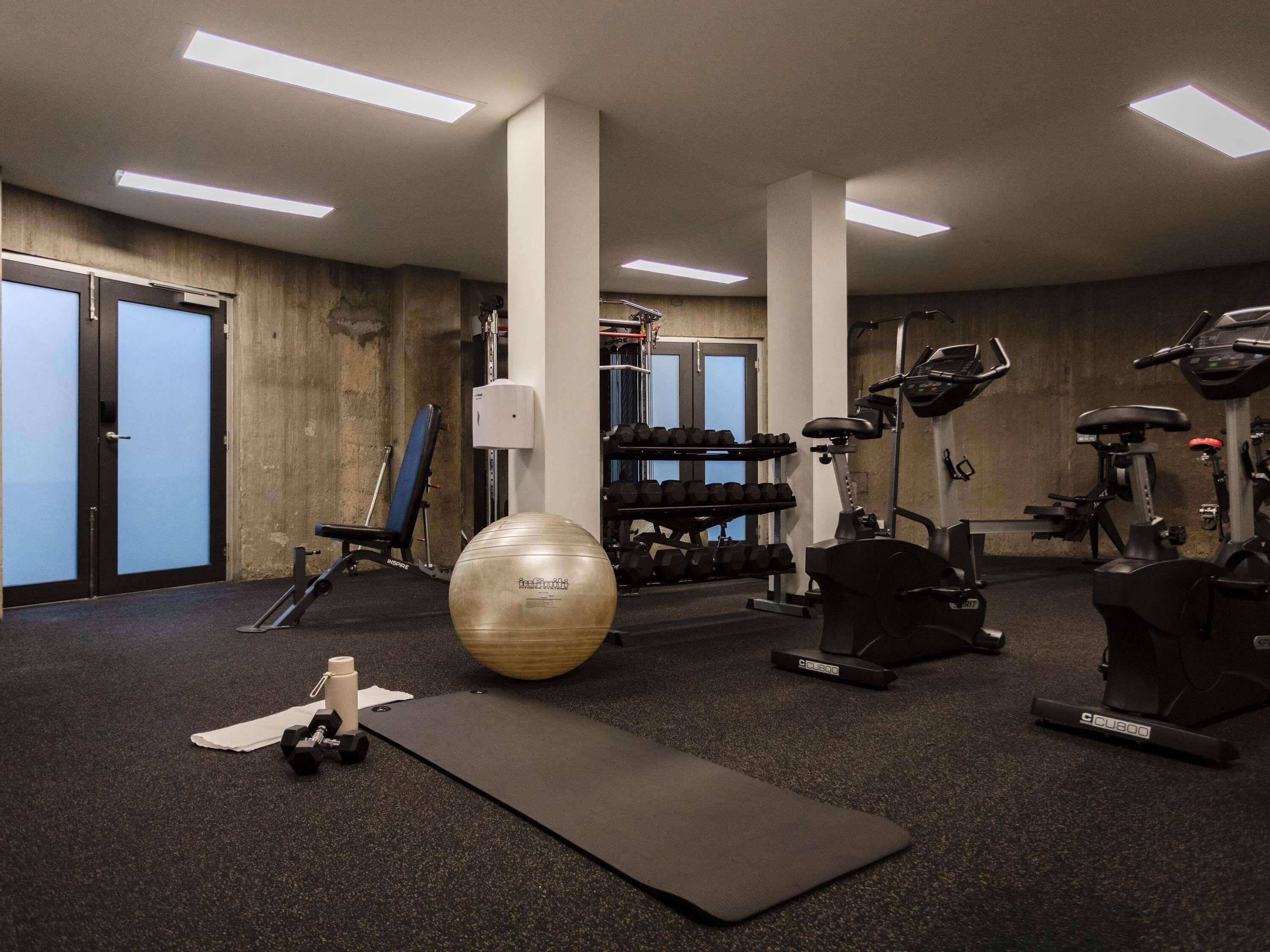A gym with exercise equipment, a large exercise ball, and a wall-mounted mirror.
