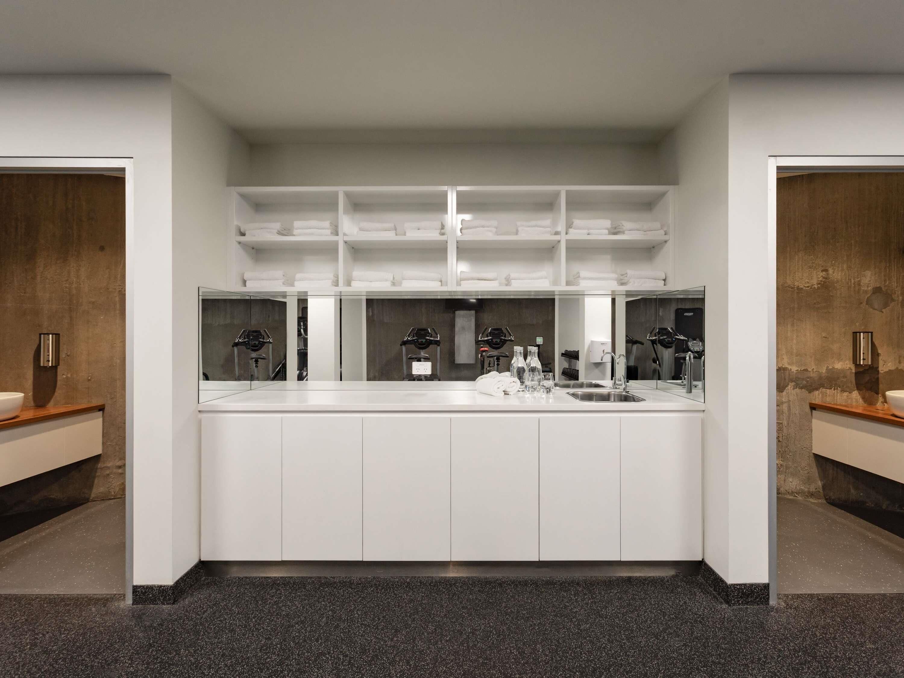 A modern bathroom with a large mirror, white cabinetry, and a granite countertop.