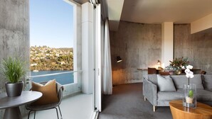 A modern living room with a balcony overlooking a body of water and a hilly landscape. - Peppers Silo Launceston (Invermay)