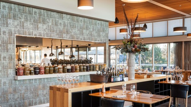 A restaurant with a bar area, wooden tables, black chairs, and hanging pendant lights. - Peppers Silo Launceston (Invermay)