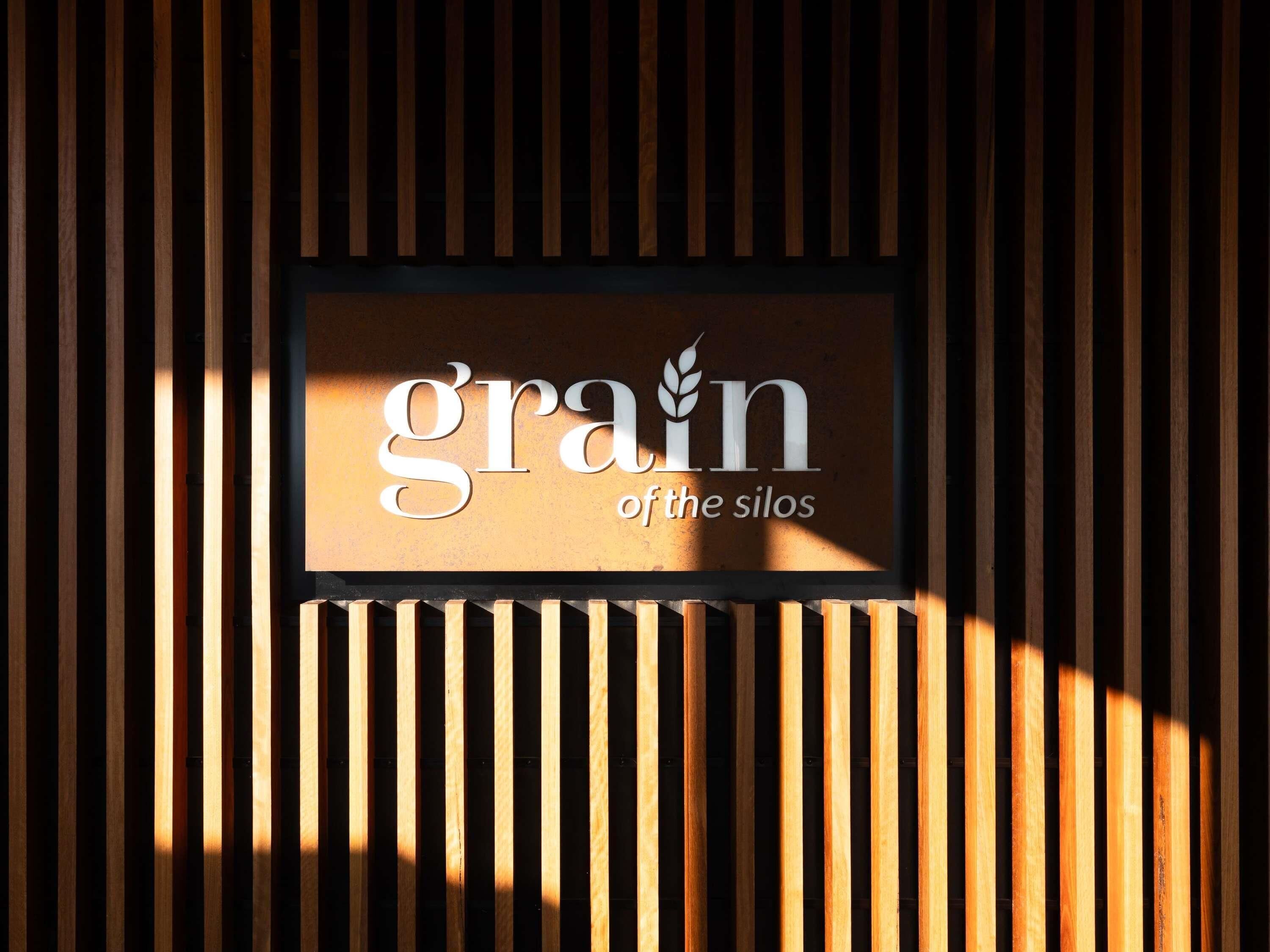 A sign with the text 'grain of the silos' against a wooden background.