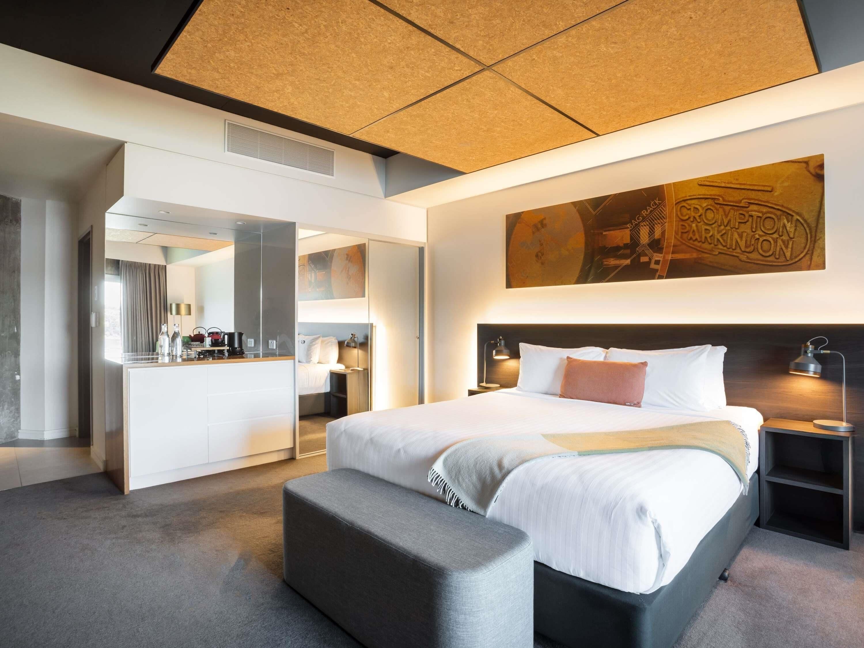 Una habitación de hotel moderna con una cama grande, un escritorio y un espejo.