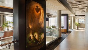 A modern lobby with a large glass wall, a central column, and a seating area with plants. - Peppers Silo Launceston (Invermay)