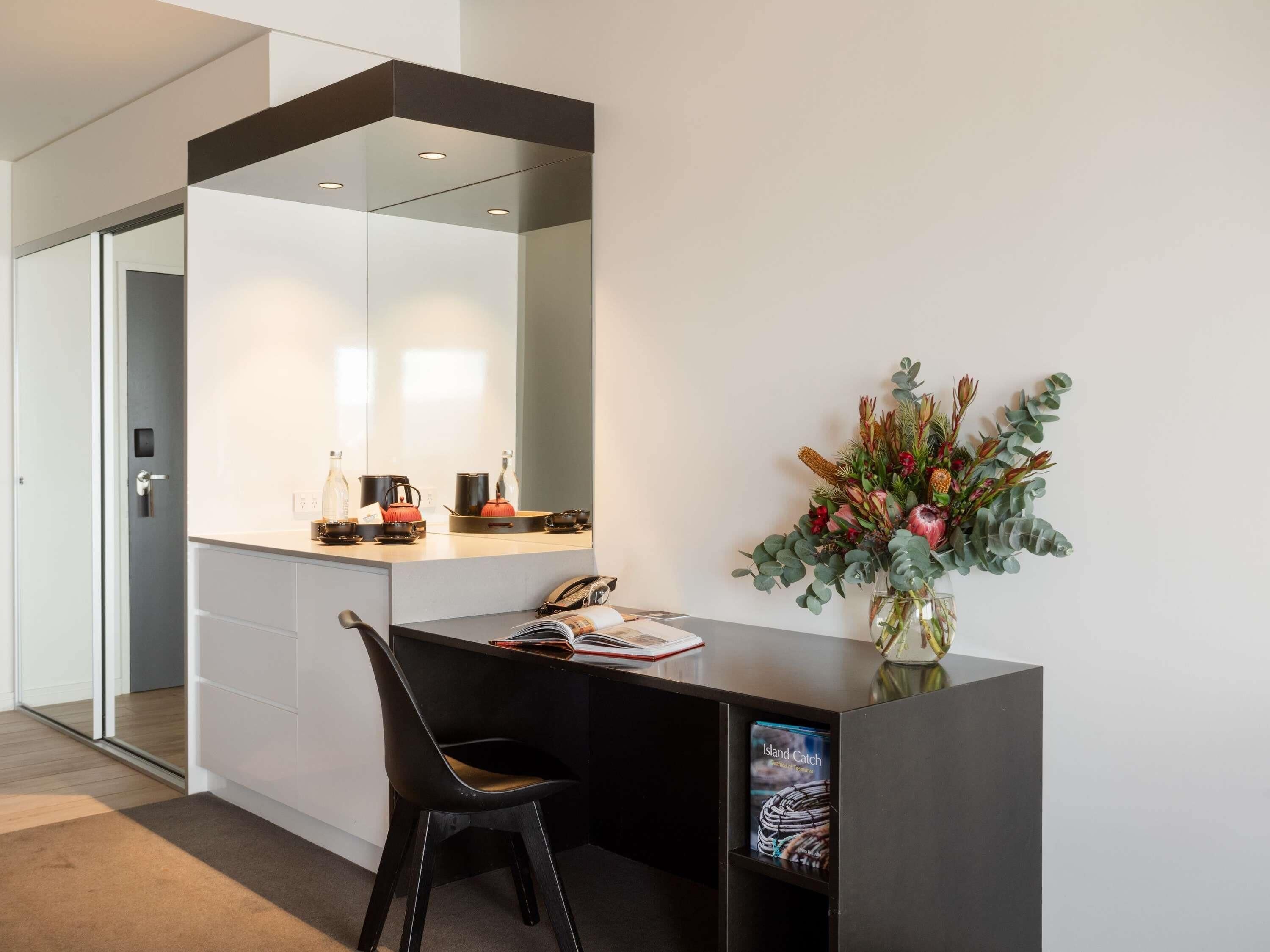 Un espace de bureau moderne comprenant un bureau, une chaise et un vase de fleurs.