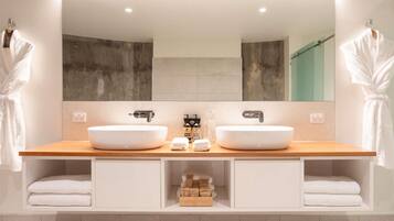 A modern bathroom with two sinks, a large mirror, and a towel rack.