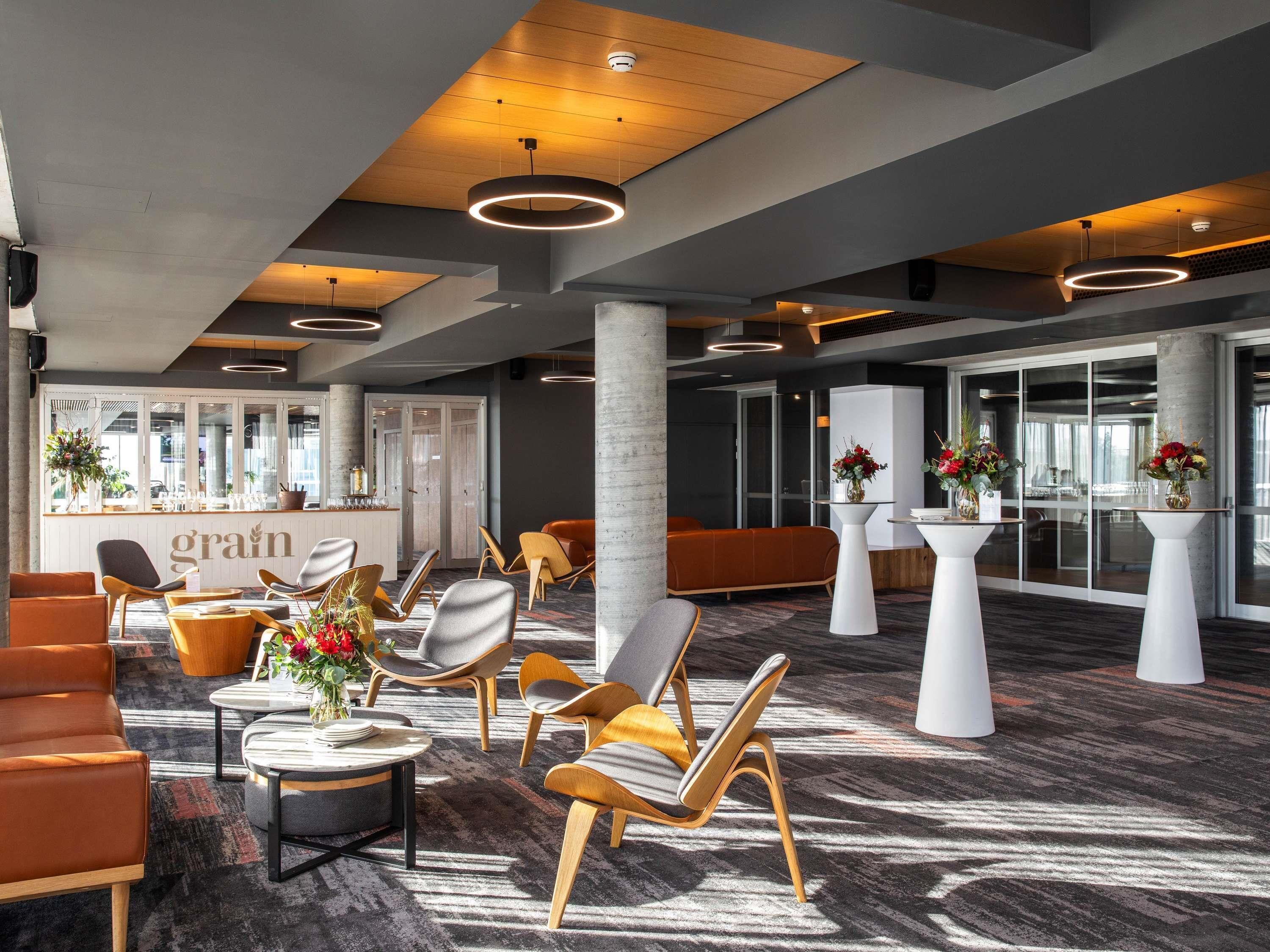 A modern hotel lobby with a reception desk, seating areas, and a patterned carpet.