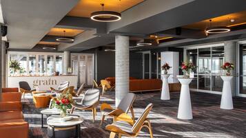 A modern hotel lobby with a reception desk, seating areas, and a patterned carpet.